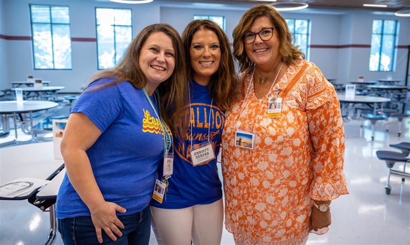 Three administrators stand together and smile